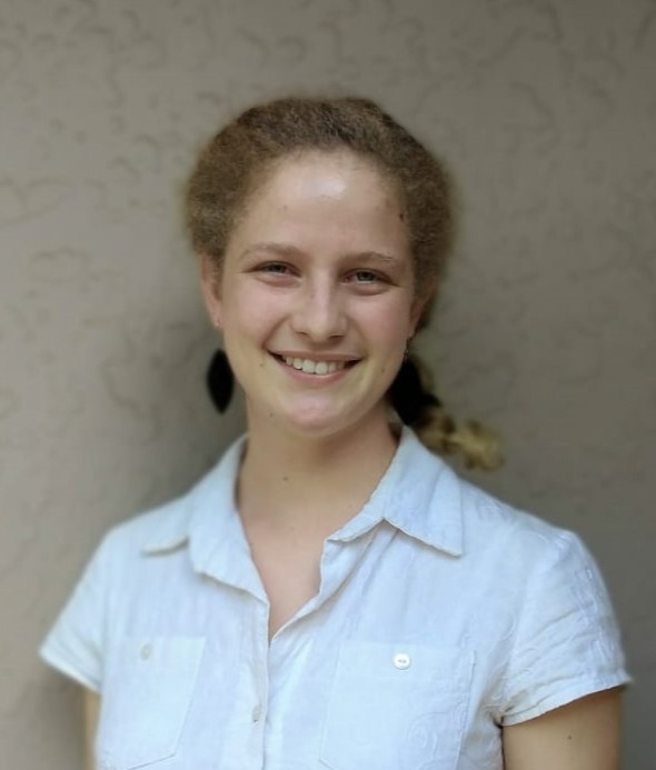 A photo of a woman wearing a white shirt against a neutral background.