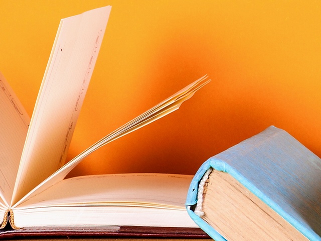 An open and a closed book agains an orange background.